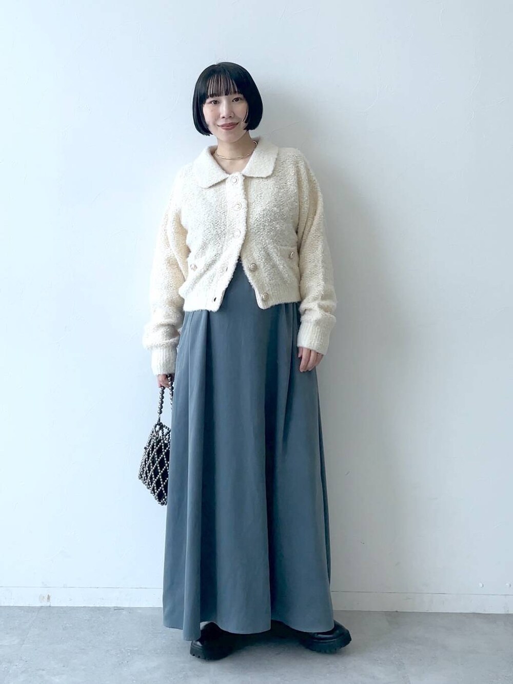 ブラック系のブーツ、ブルー系のワンピース、ホワイト系のカーディガン/ボレロを着用したレディースの秋コーディネートの2枚目の写真