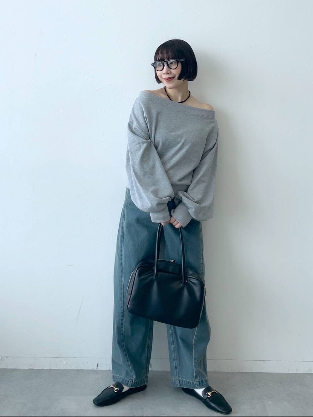 ブルー系のデニムパンツ、ブラック系のボストンバッグ、グレー系のスウェットを着用したレディースの秋コーディネートの2枚目の写真