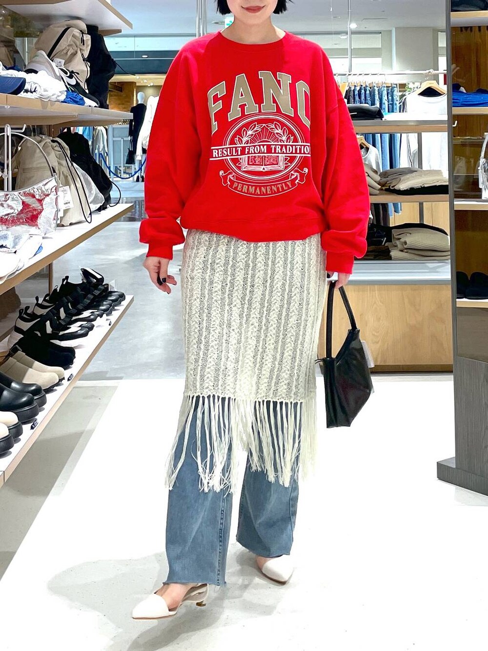 レッド系のスウェット、ブルー系のデニムパンツ、ホワイト系のスカートを着用したレディースの冬コーディネートの2枚目の写真