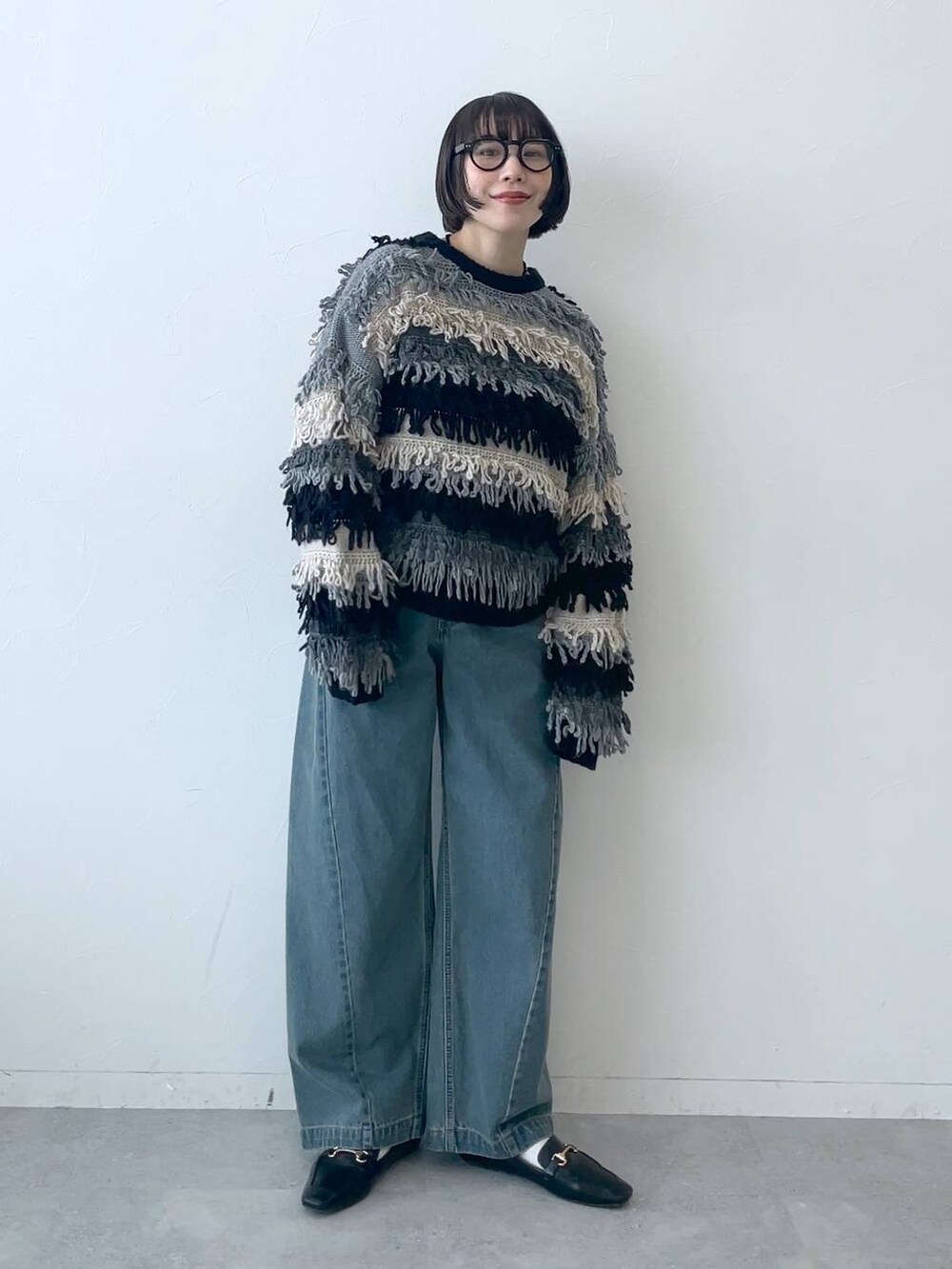 ブルー系のデニムパンツ、ブラック系のニット/セーターを着用したレディースの秋コーディネートの2枚目の写真