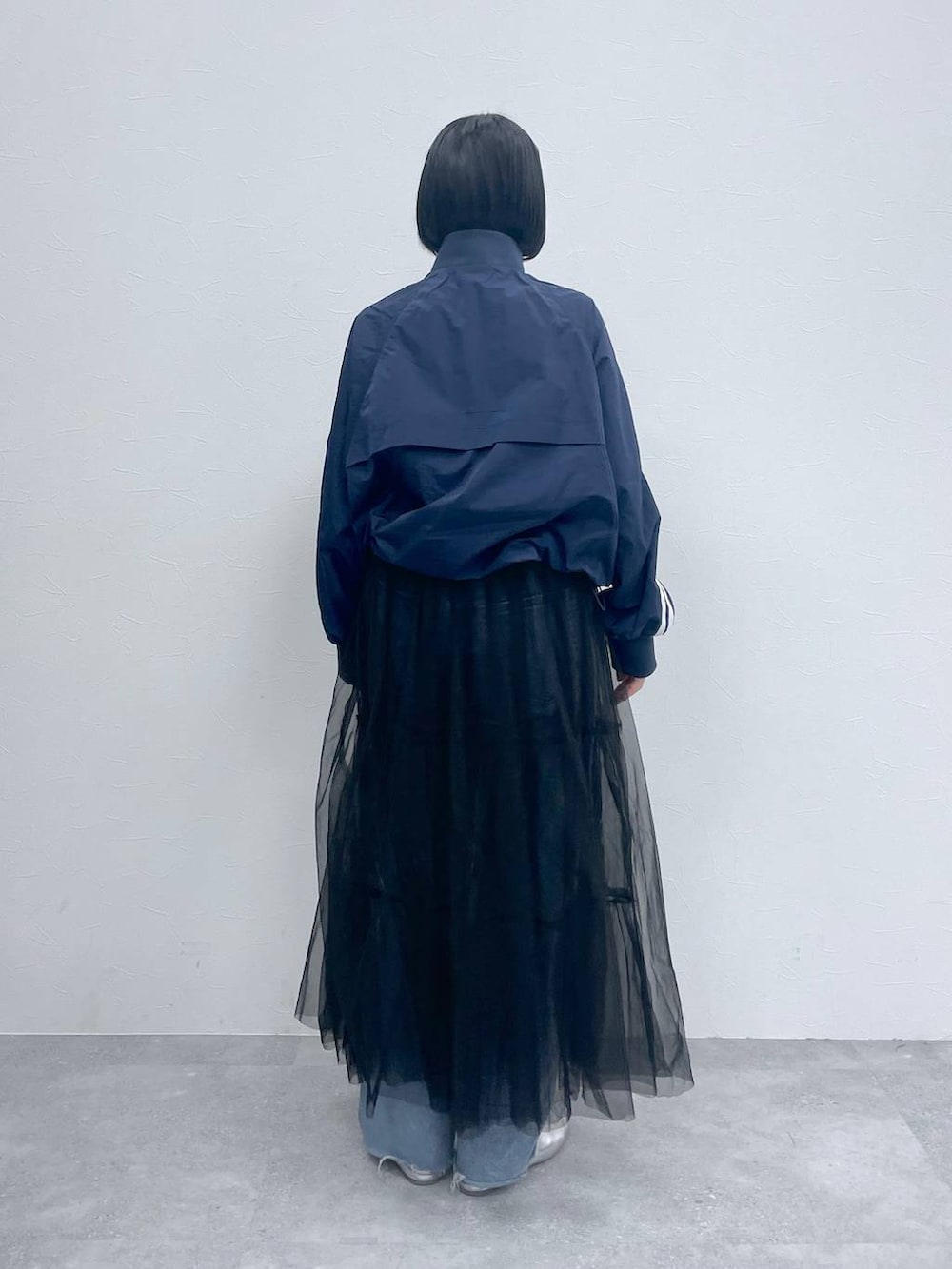 ブラック系のスカート、ブルー系のデニムパンツ、ブルー系のブルゾンを着用したレディースの春コーディネートの3枚目の写真