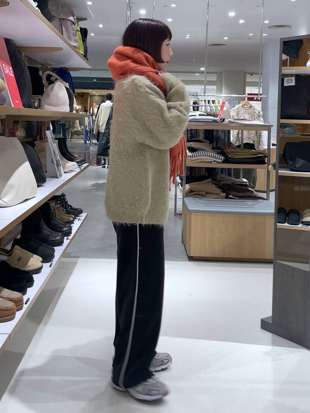 ベージュ系のカーディガン/ボレロ、ブラック系のその他パンツ、オレンジ系のストール/ショールを着用したレディースの冬コーディネートの3枚目の写真