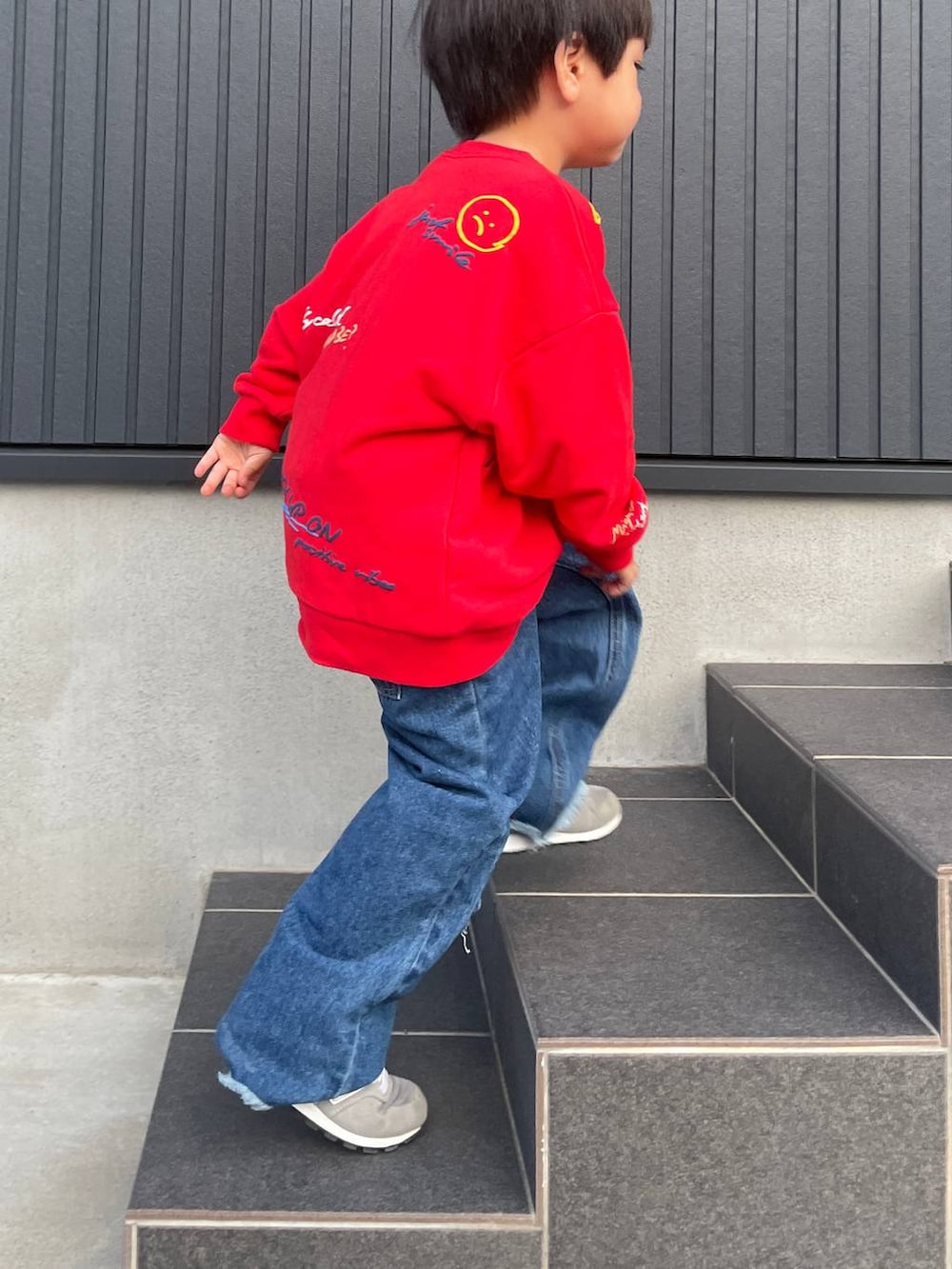ブルー系のデニムパンツ、レッド系のスウェットを着用したキッズの秋コーディネートの3枚目の写真