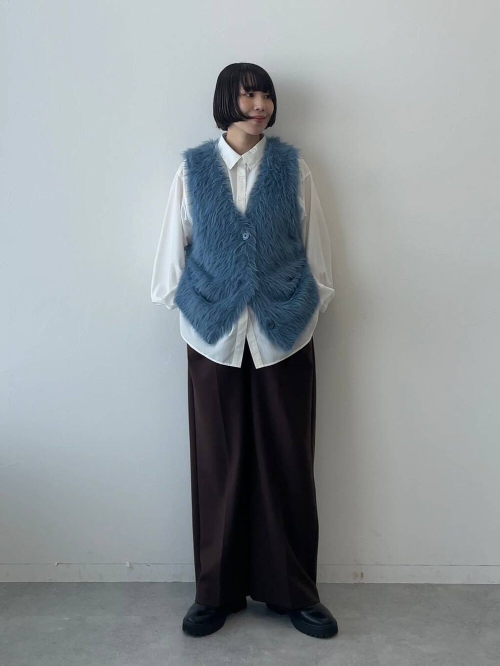 ブラウン系のスラックス、ホワイト系のシャツ/ブラウス、ブルー系のベストを着用したレディースの秋コーディネートの2枚目の写真