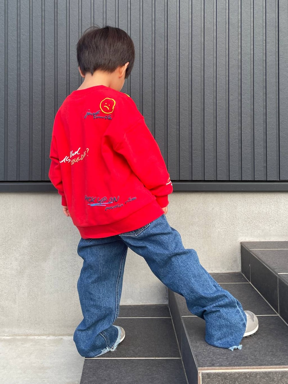 ブルー系のデニムパンツ、レッド系のスウェットを着用したキッズの秋コーディネートの2枚目の写真