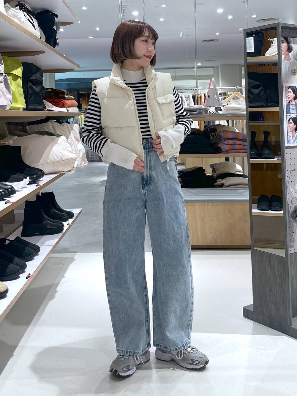 ブルー系のデニムパンツ、ホワイト系のベスト、ホワイト系のニット/セーターを着用したレディースの冬コーディネートの2枚目の写真