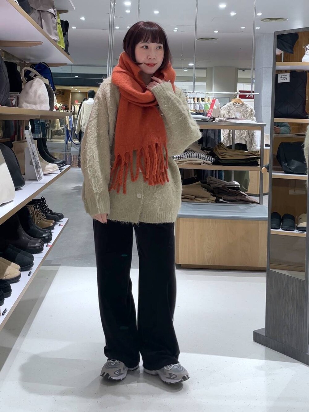 ベージュ系のカーディガン/ボレロ、ブラック系のその他パンツ、オレンジ系のストール/ショールを着用したレディースの冬コーディネートの2枚目の写真