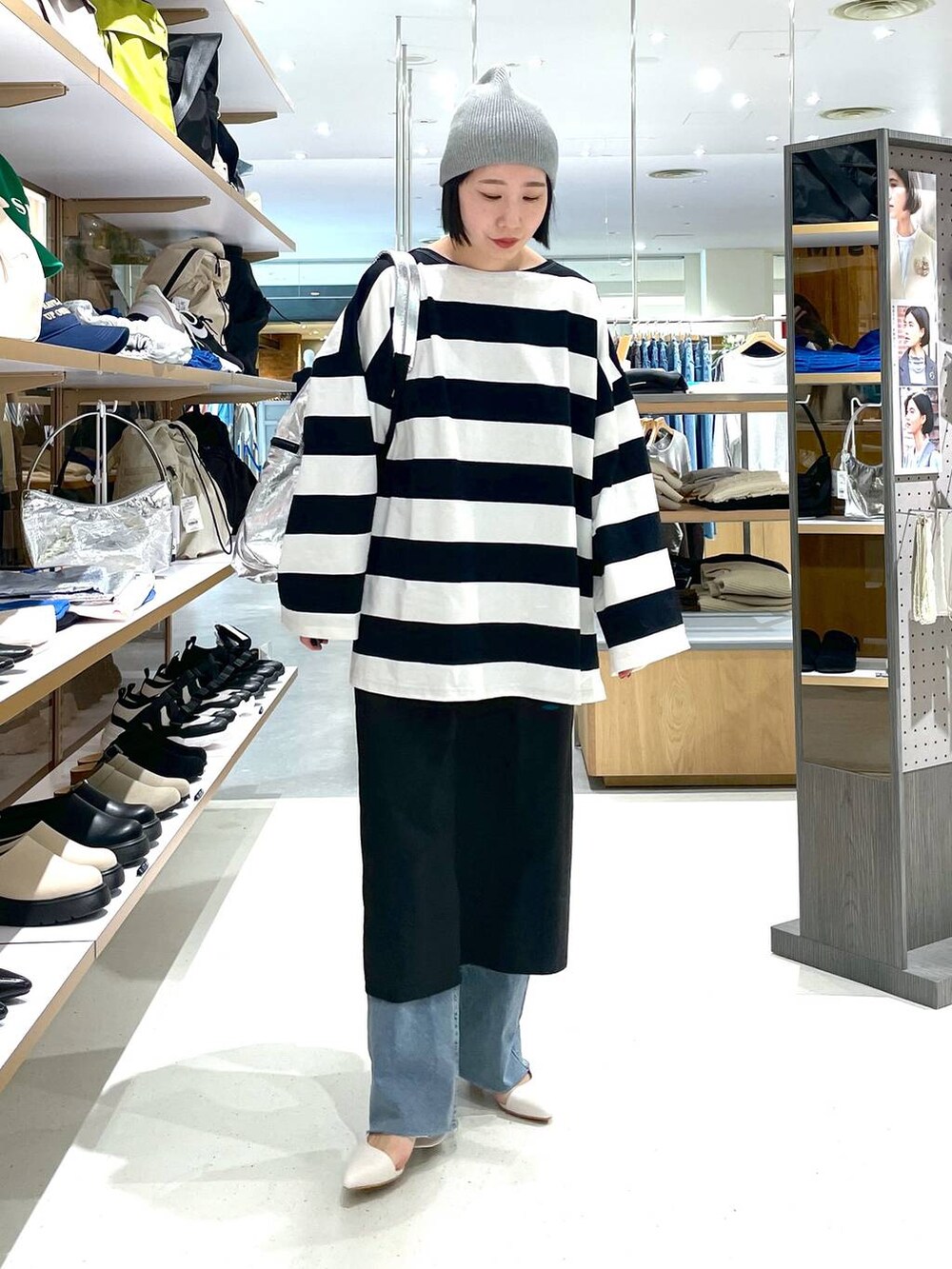 シルバー系のショルダーバッグ、ブラック系のスカート、ブルー系のデニムパンツを着用したレディースの冬コーディネートの2枚目の写真