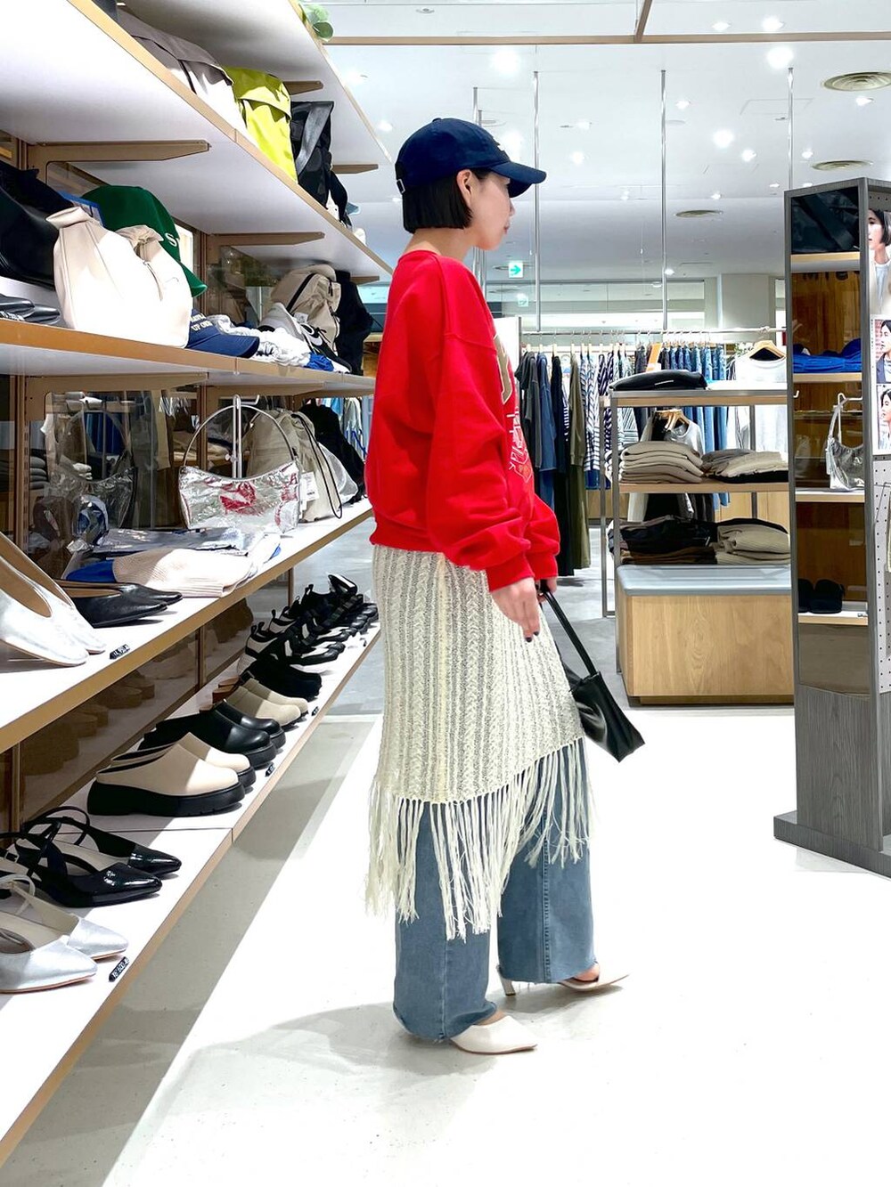 レッド系のスウェット、ブルー系のデニムパンツ、ホワイト系のスカートを着用したレディースの冬コーディネートの4枚目の写真