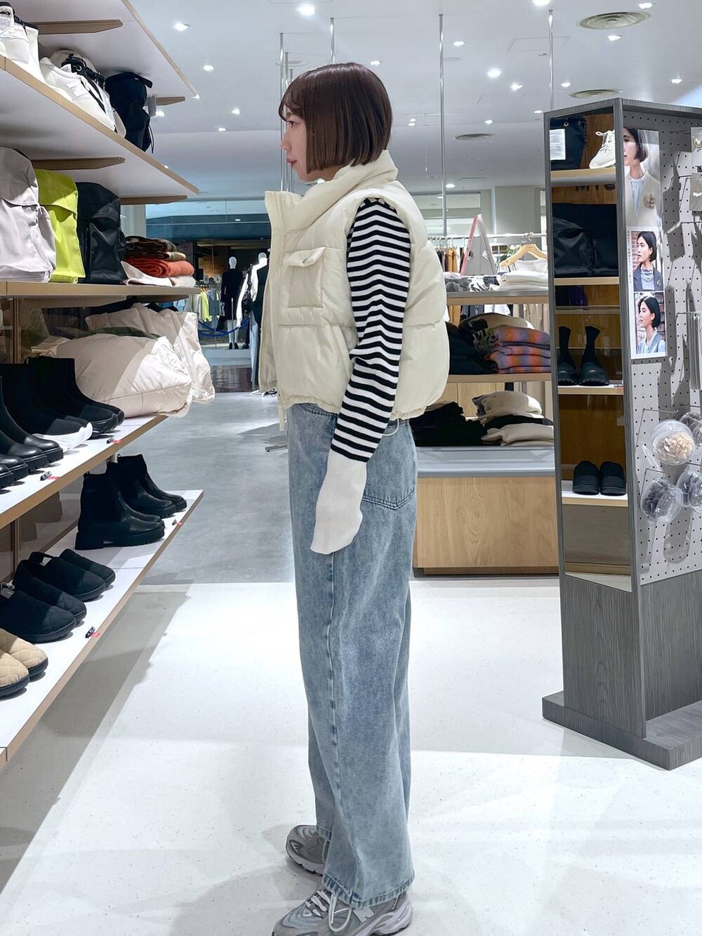 ブルー系のデニムパンツ、ホワイト系のベスト、ホワイト系のニット/セーターを着用したレディースの冬コーディネートの3枚目の写真