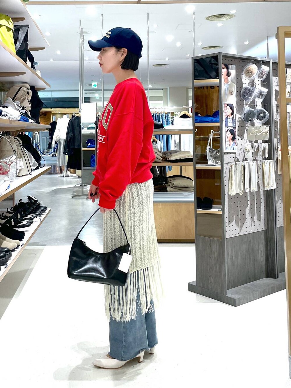 レッド系のスウェット、ブルー系のデニムパンツ、ホワイト系のスカートを着用したレディースの冬コーディネートの3枚目の写真