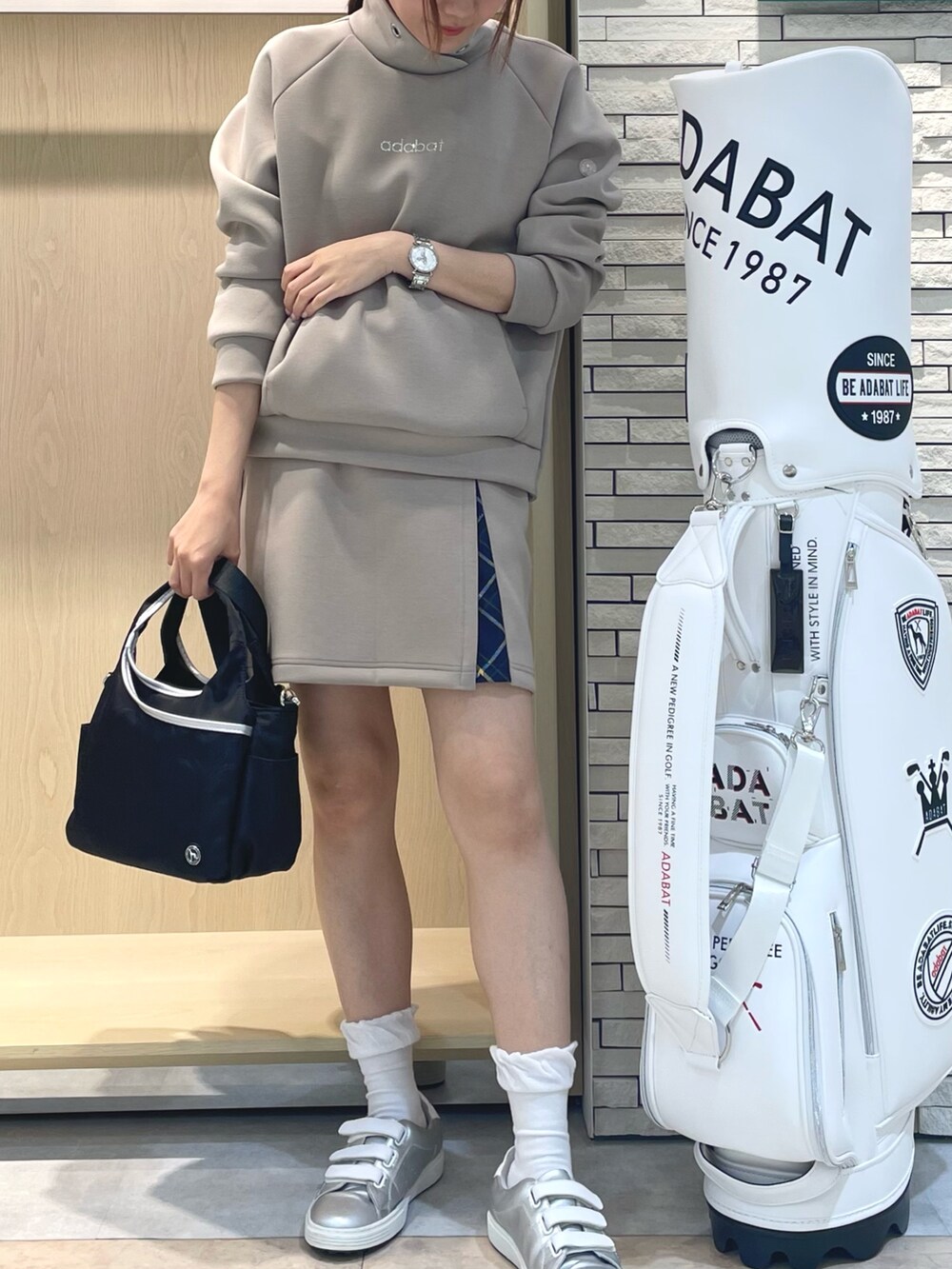 ベージュ系のTシャツ/カットソー、ベージュ系のスカート、ブラック系のハンドバッグを着用したレディースの秋コーディネートの4枚目の写真