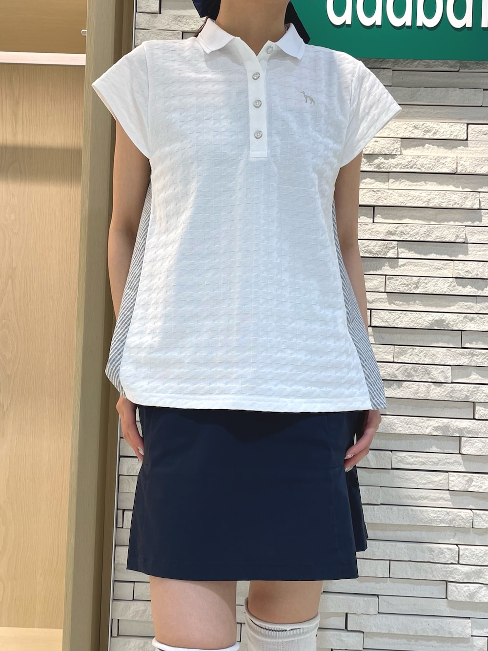 ブルー系のスカート、ホワイト系のポロシャツ、レッド系のハンドバッグを着用したレディースの秋コーディネートの4枚目の写真