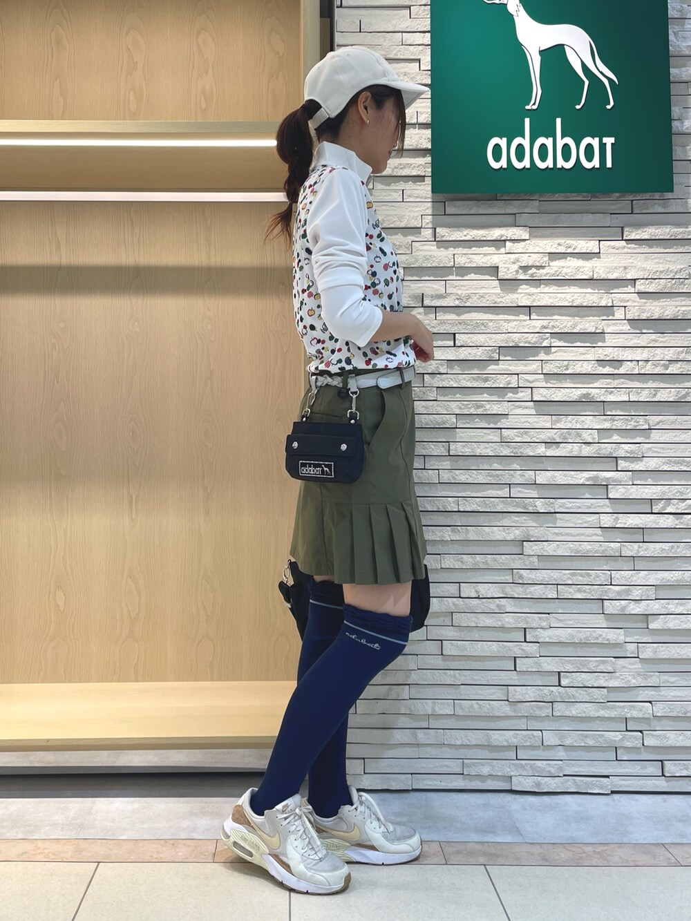 グリーン系のスカート、レッド系のTシャツ/カットソー、ブラック系のハンドバッグを着用したレディースの秋コーディネートの2枚目の写真