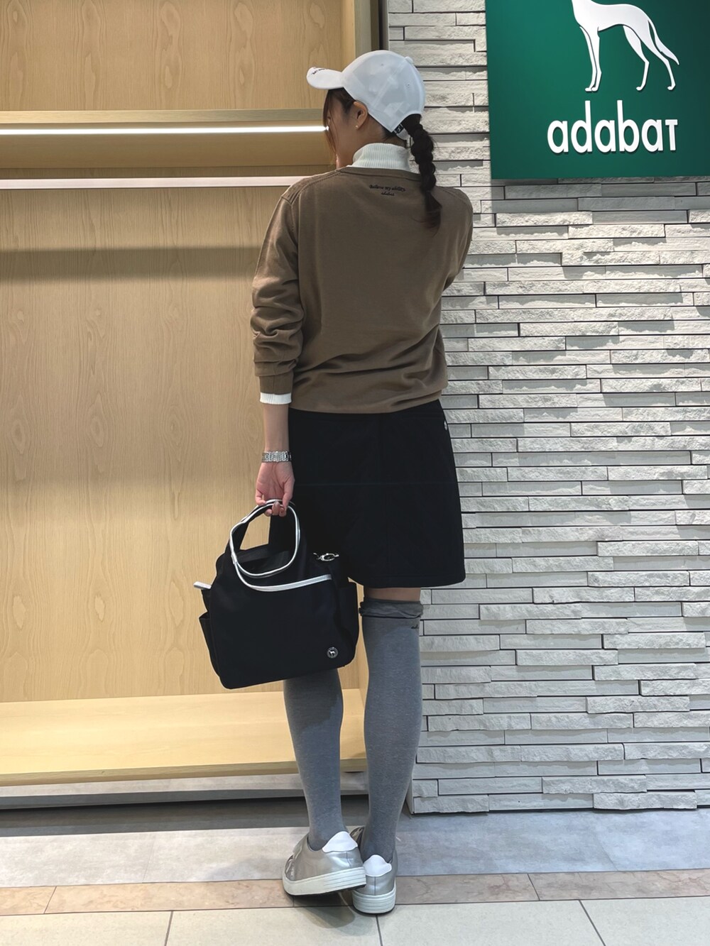 ブラック系のスカート、ベージュ系のニット/セーター、ブラック系のハンドバッグを着用したレディースの春コーディネートの3枚目の写真