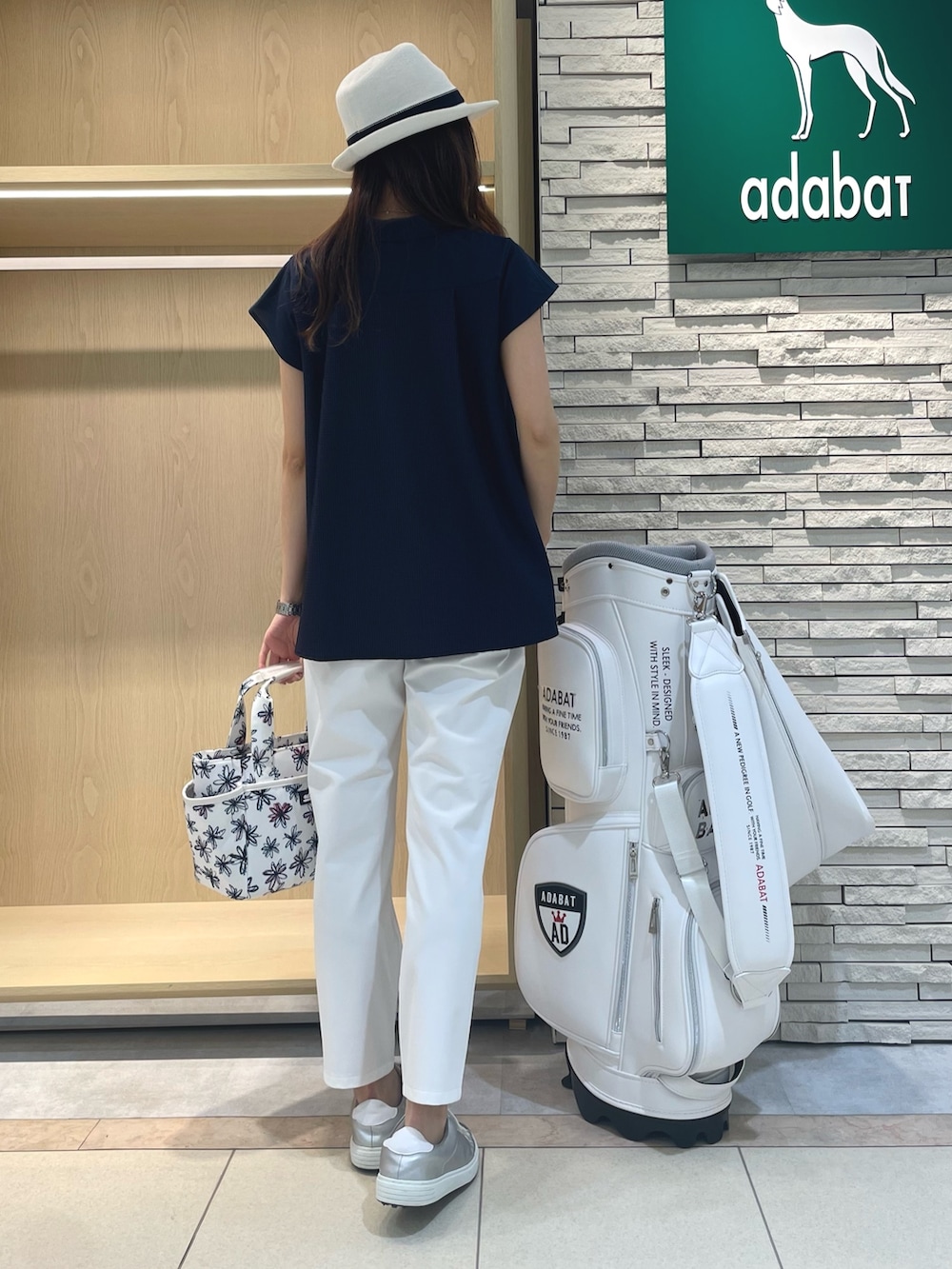 ブルー系のポロシャツ、ホワイト系のその他パンツ、ホワイト系のハンドバッグを着用したレディースの春コーディネートの2枚目の写真