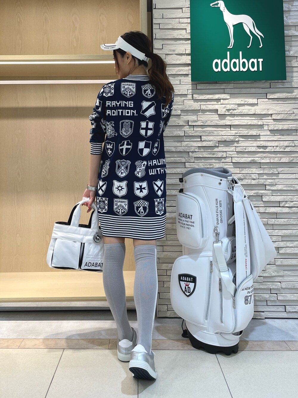 ブルー系のワンピース、ホワイト系のハンドバッグ、ホワイト系のサンバイザーを着用したレディースの秋コーディネートの2枚目の写真