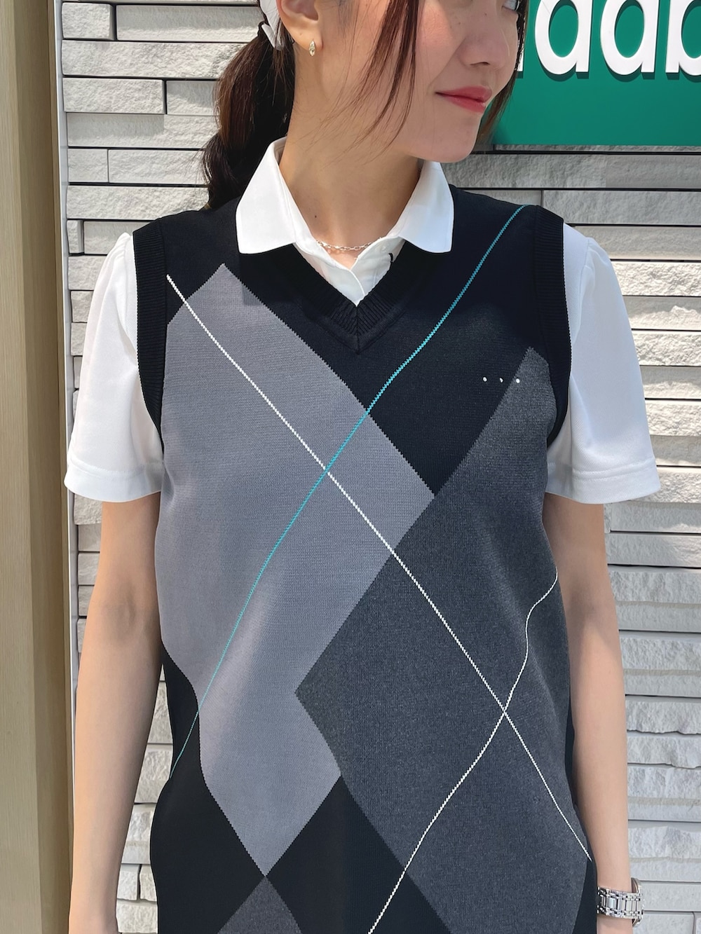 ブラック系のベスト、ホワイト系のポロシャツ、グレー系のスカートを着用したレディースの春コーディネートの3枚目の写真