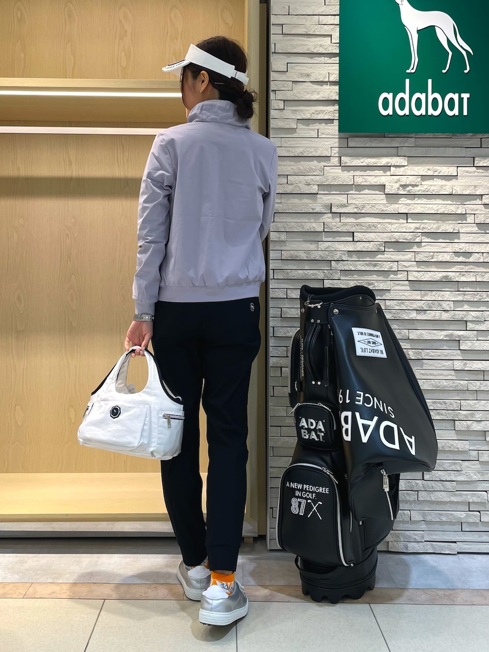 グレー系のブルゾン、ブルー系のTシャツ/カットソー、ホワイト系のトートバッグを着用したレディースの春コーディネートの2枚目の写真