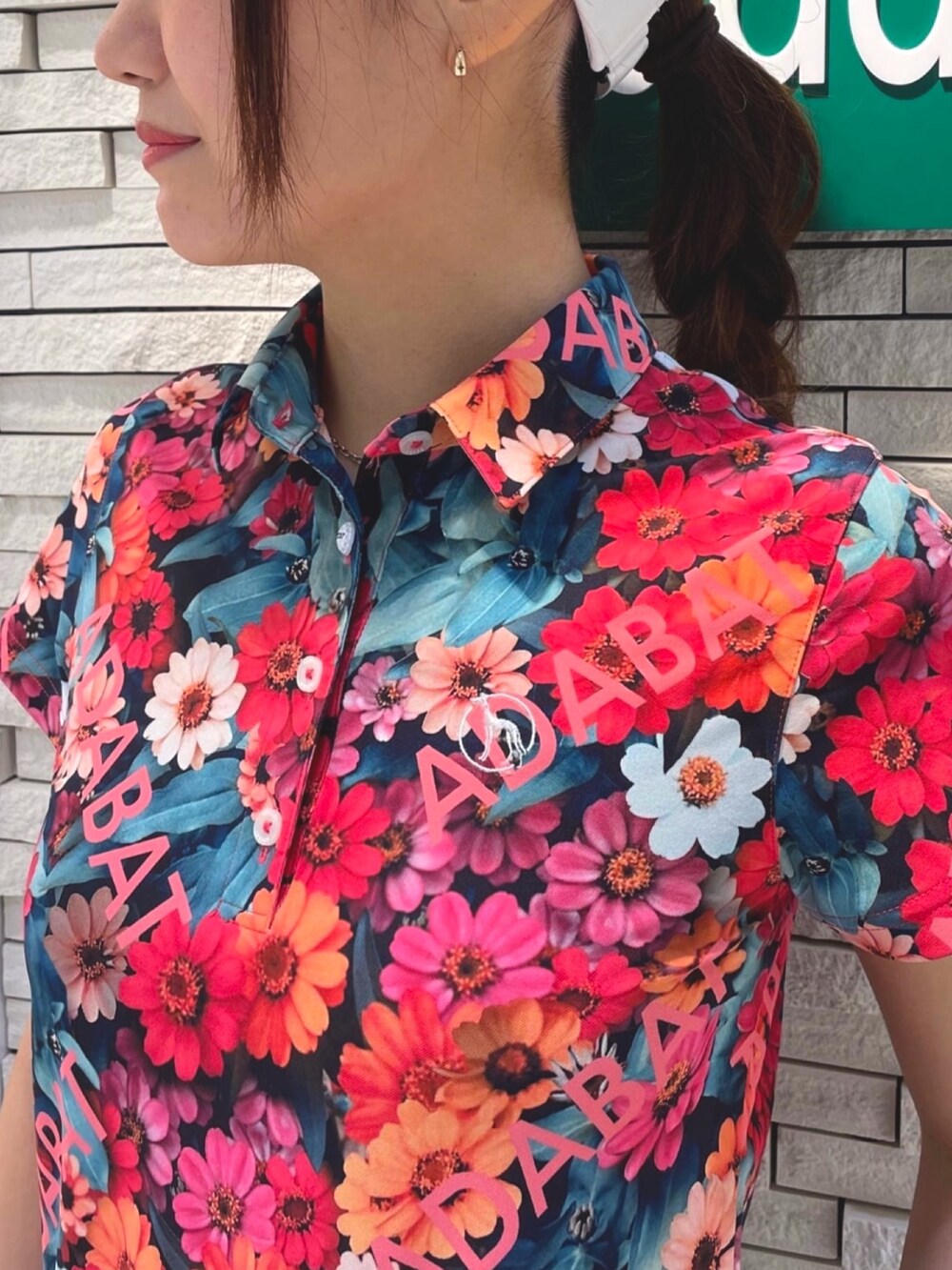 ブルー系のスカート、ピンク系のポロシャツ、ホワイト系のサンバイザーを着用したレディースの夏コーディネートの4枚目の写真