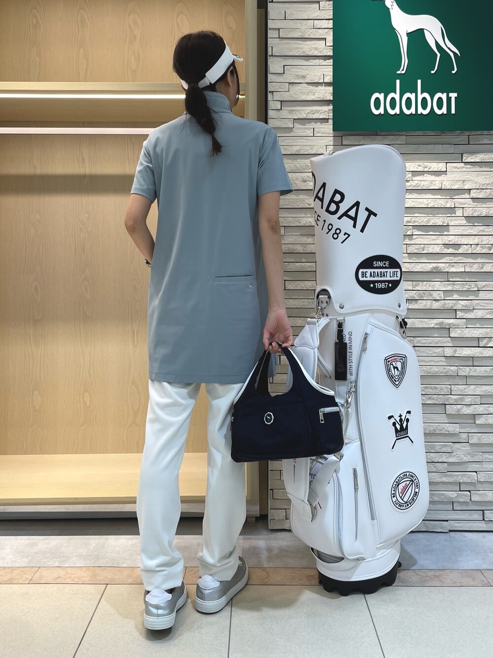 ブルー系のチュニック、ホワイト系のその他パンツ、ブルー系のトートバッグを着用したレディースの春コーディネートの2枚目の写真