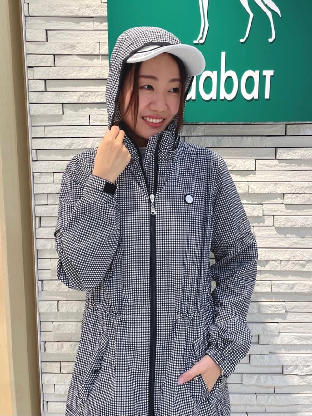 ブルー系のトートバッグ、ホワイト系のブルゾン、ホワイト系のサンバイザーを着用したレディースの夏コーディネートの4枚目の写真