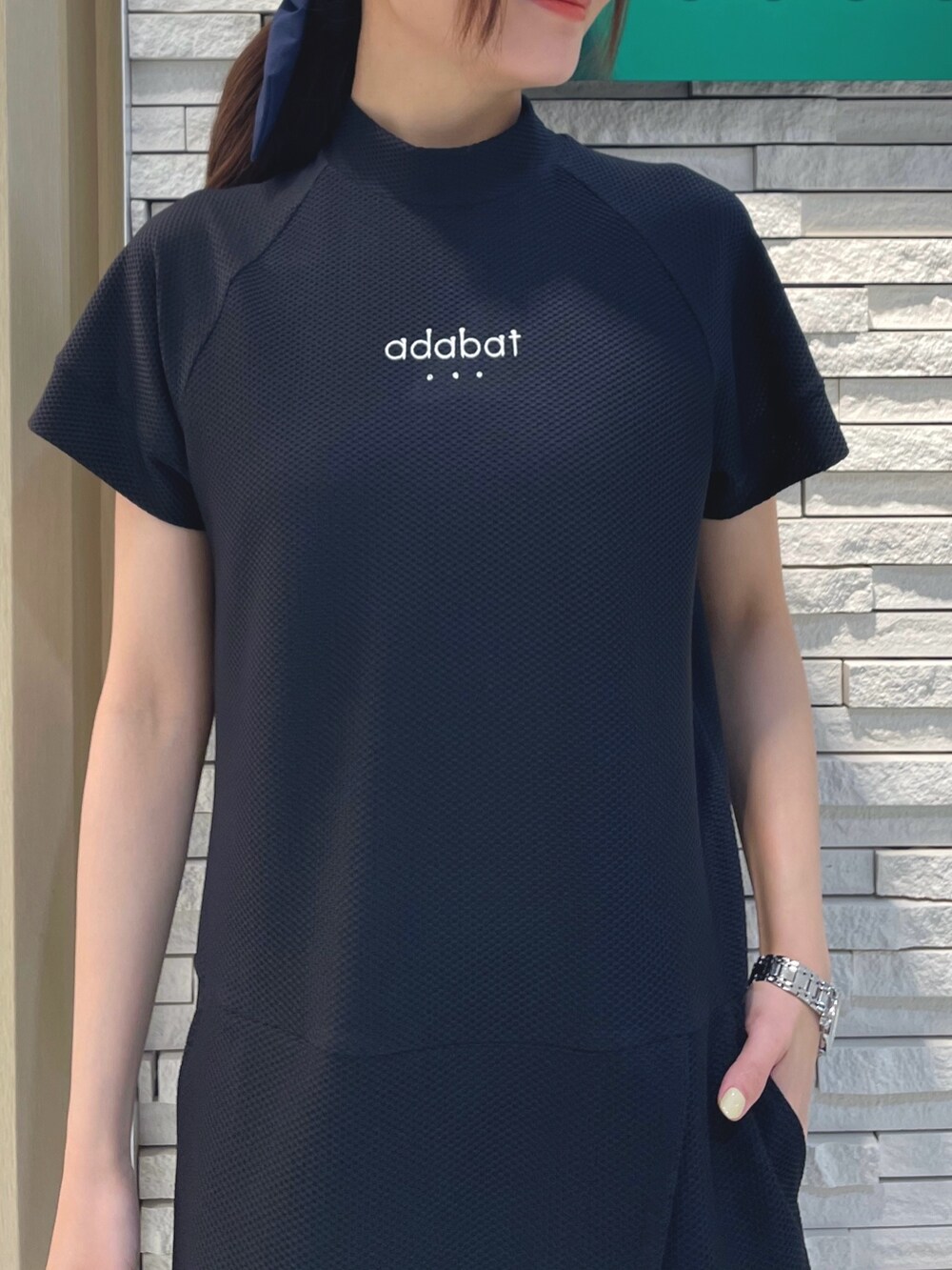 ブラック系のワンピース、ブルー系のハンドバッグ、ホワイト系のキャップを着用したレディースの春コーディネートの3枚目の写真