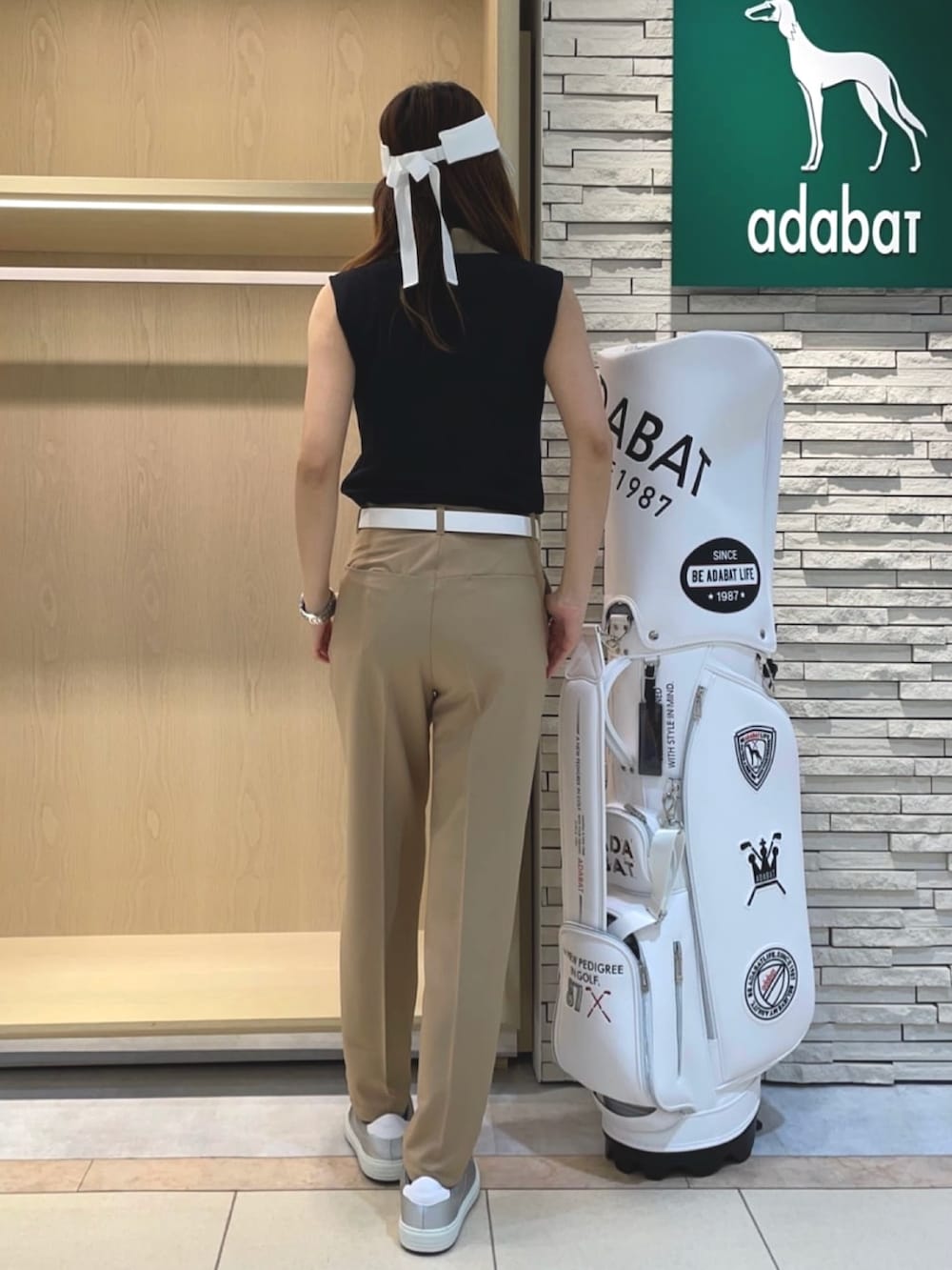 ベージュ系のその他パンツ、ブルー系のポロシャツ、ホワイト系のサンバイザーを着用したレディースの夏コーディネートの3枚目の写真