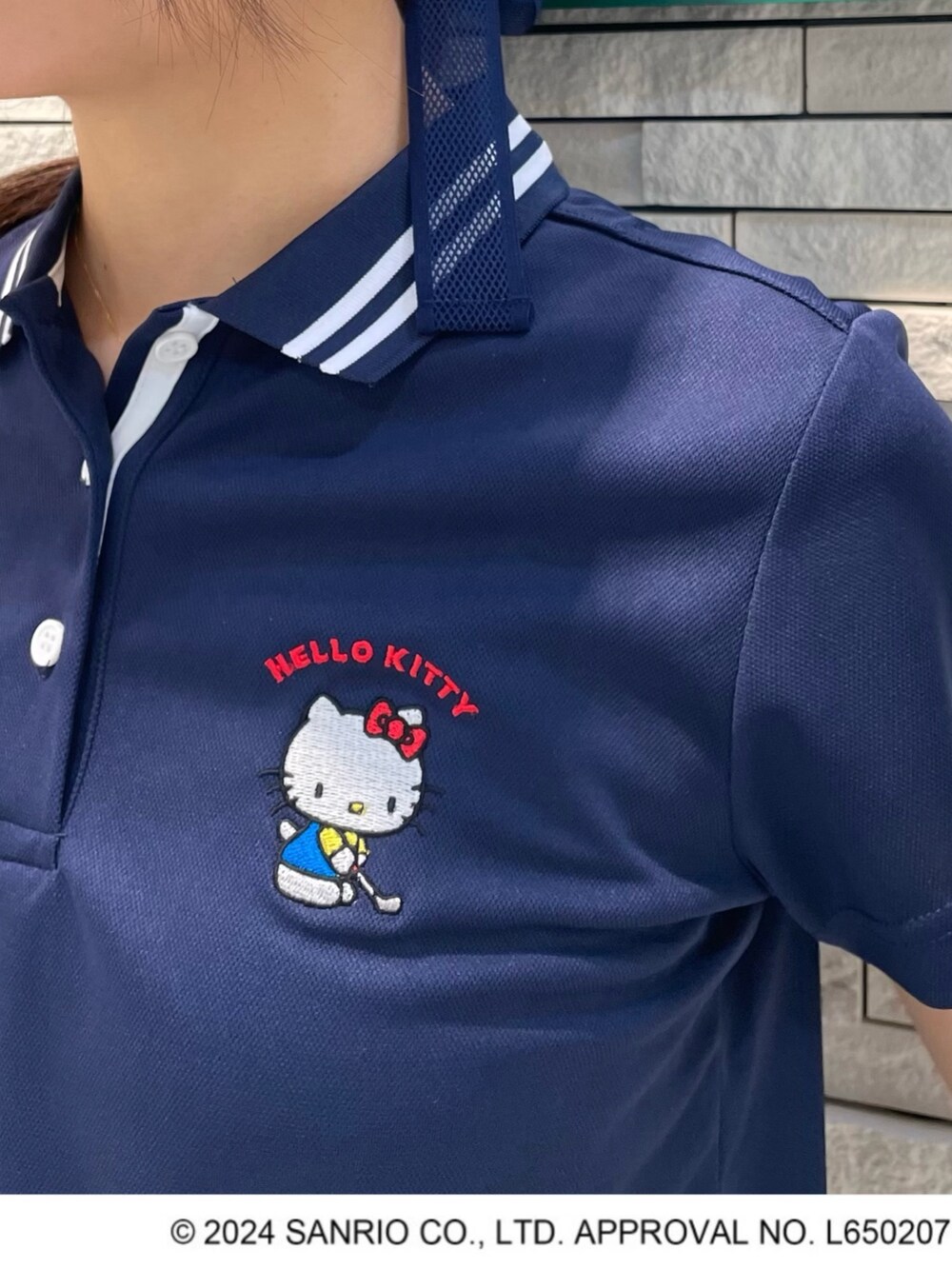 ブルー系のポロシャツ、ホワイト系のスカート、グリーン系のトートバッグを着用したレディースの夏コーディネートの2枚目の写真