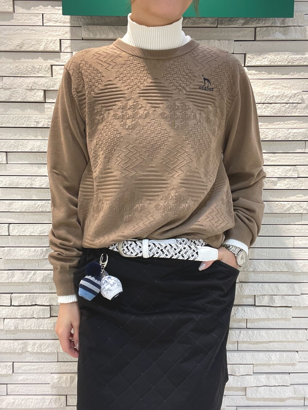 ブラック系のスカート、ベージュ系のニット/セーター、ブラック系のハンドバッグを着用したレディースの春コーディネートの4枚目の写真