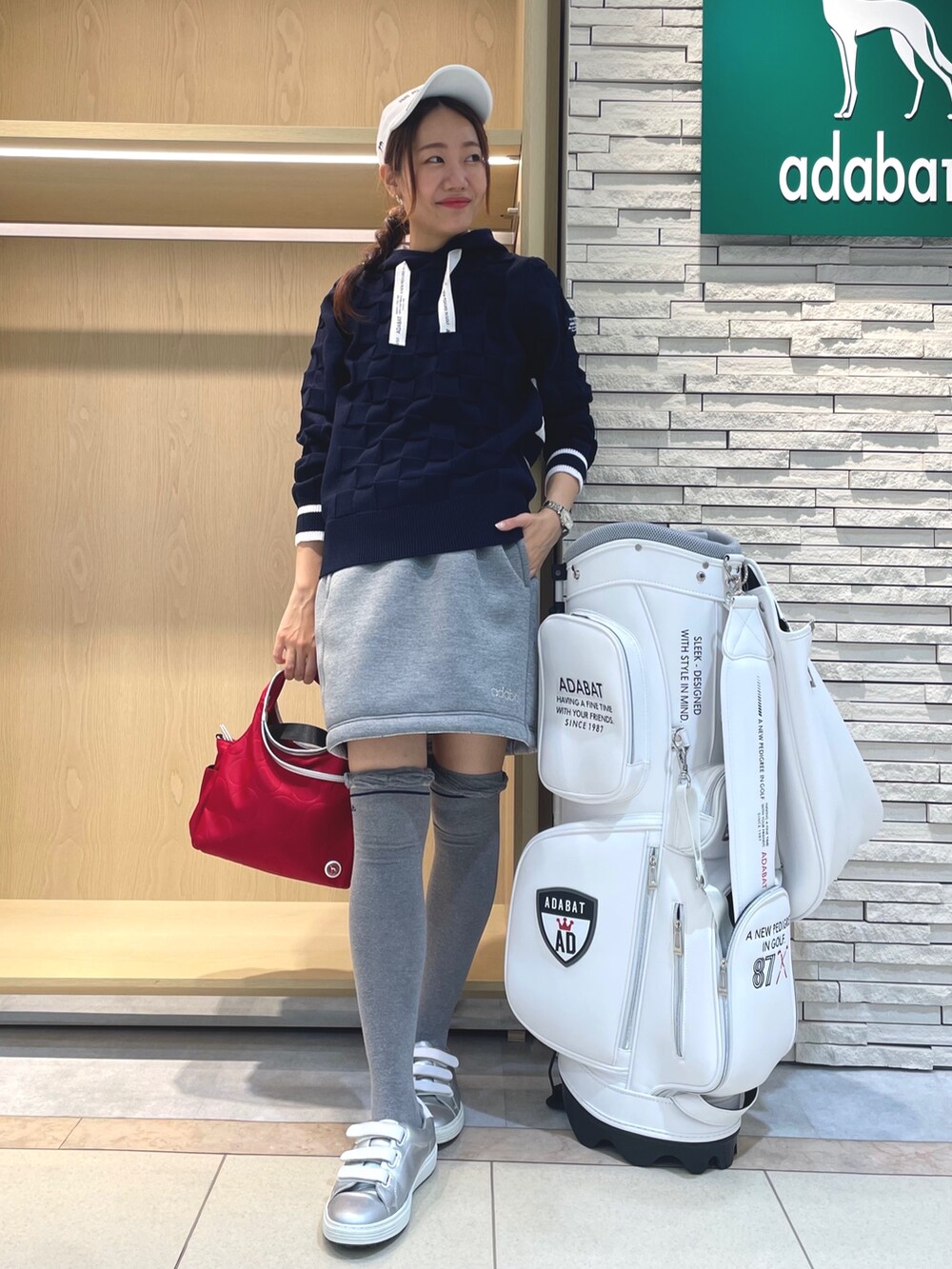 グレー系のスカート、ブルー系のニット/セーター、レッド系のハンドバッグを着用したレディースの秋コーディネートの2枚目の写真