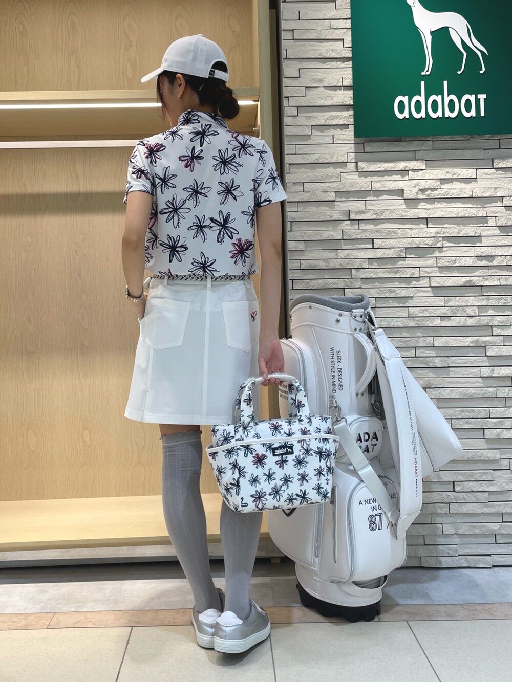 ホワイト系のポロシャツ、ホワイト系のスカート、ホワイト系のハンドバッグを着用したレディースの春コーディネートの2枚目の写真