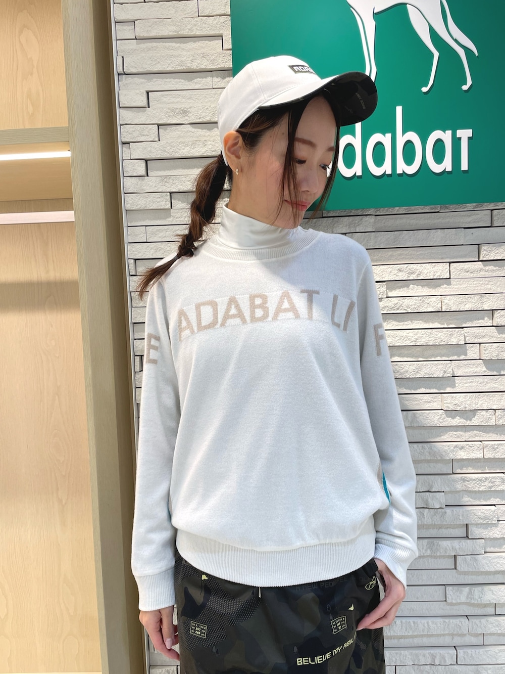 グリーン系のスカート、ホワイト系のニット/セーター、ホワイト系のTシャツ/カットソーを着用したレディースの冬コーディネートの4枚目の写真