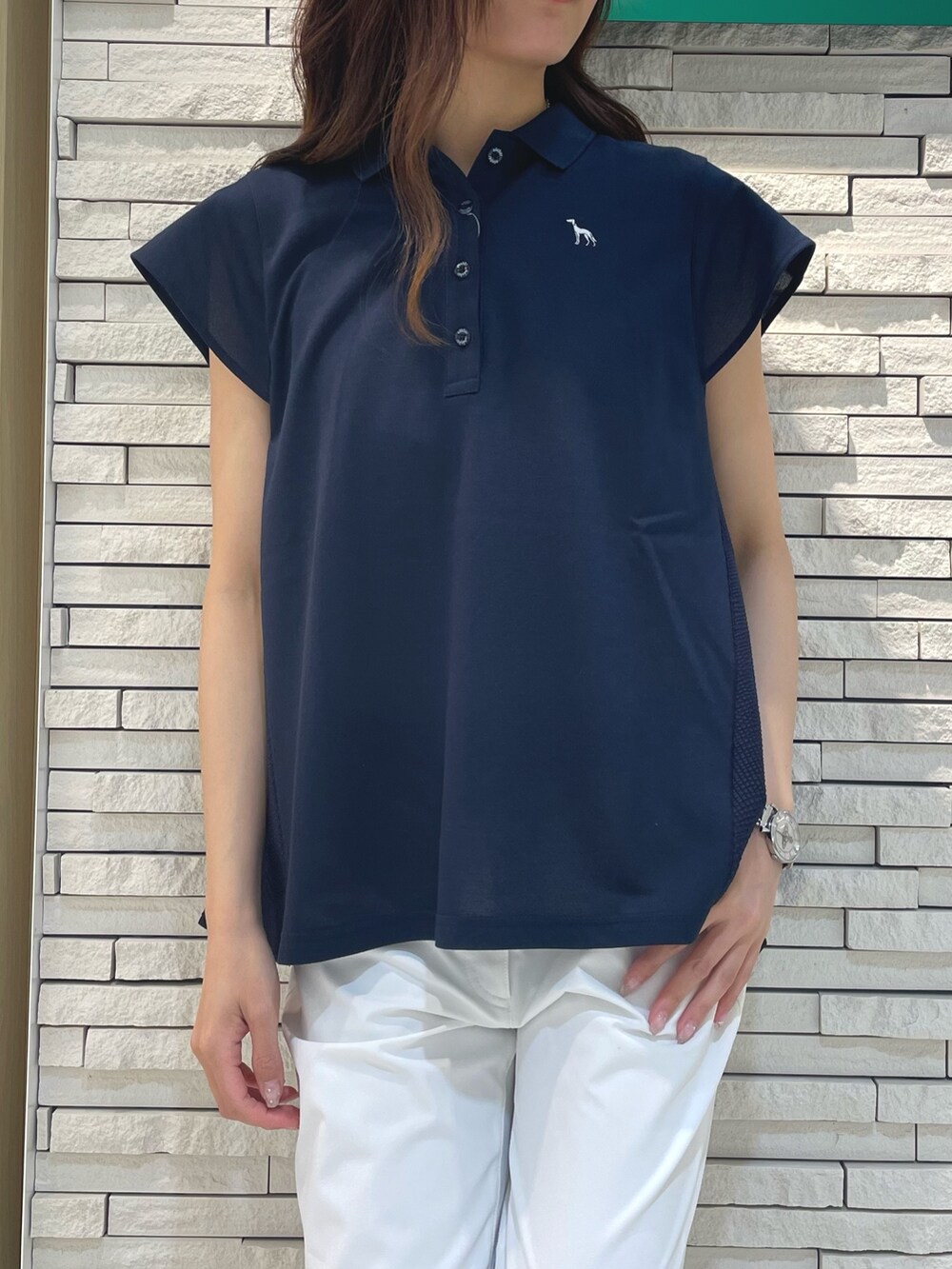 ブルー系のポロシャツ、ホワイト系のその他パンツ、ホワイト系のハンドバッグを着用したレディースの春コーディネートの3枚目の写真