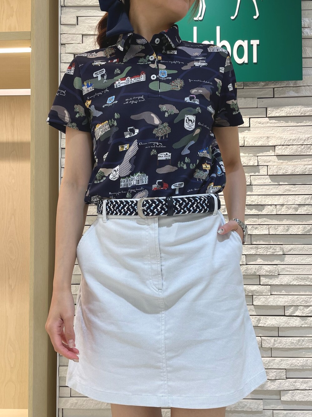 ブルー系のポロシャツ、グレー系のスカート、ブラック系のハンドバッグを着用したレディースの秋コーディネートの4枚目の写真