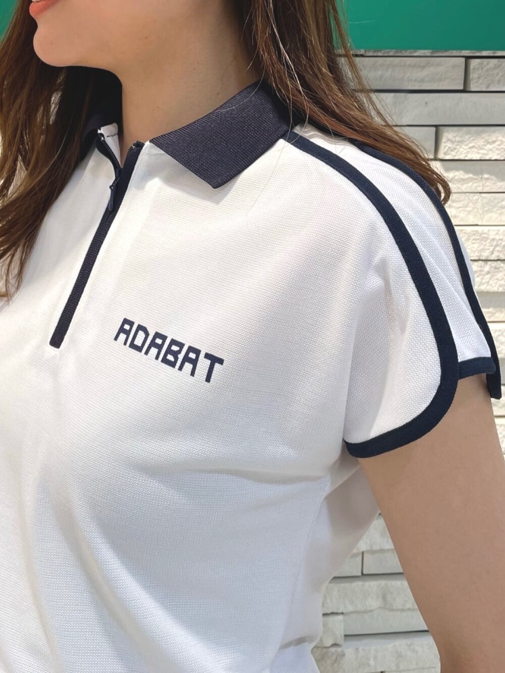 ホワイト系のスカート、ホワイト系のポロシャツ、ホワイト系のスニーカーを着用したレディースの夏コーディネートの4枚目の写真