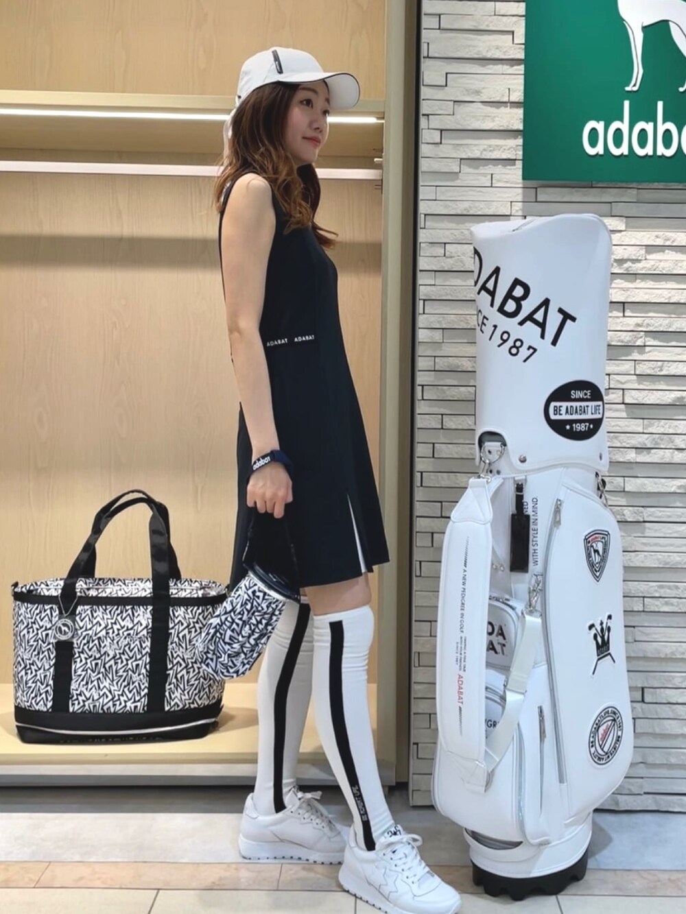 ブラック系のワンピース、ホワイト系のスニーカー、ホワイト系のソックス/靴下を着用したレディースの夏コーディネートの2枚目の写真