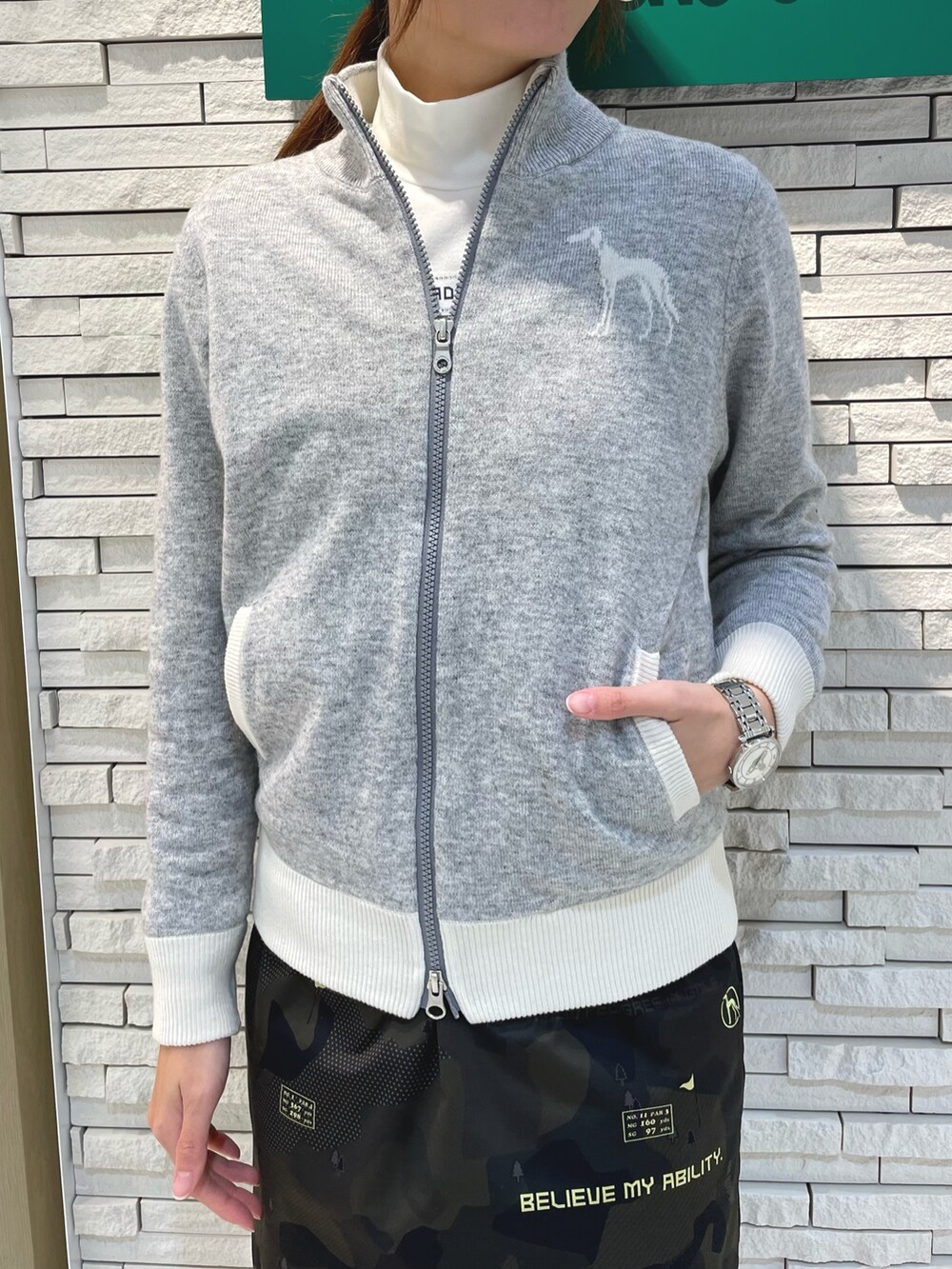 グリーン系のスカート、グレー系のニット/セーター、ホワイト系のTシャツ/カットソーを着用したレディースの冬コーディネートの4枚目の写真