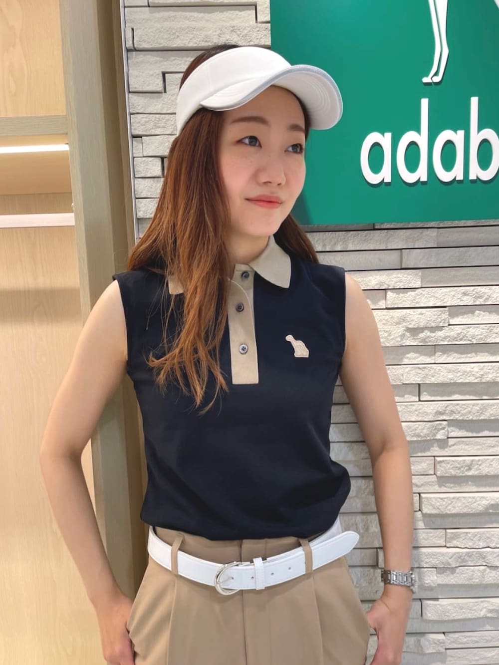 ベージュ系のその他パンツ、ブルー系のポロシャツ、ホワイト系のサンバイザーを着用したレディースの夏コーディネートの4枚目の写真