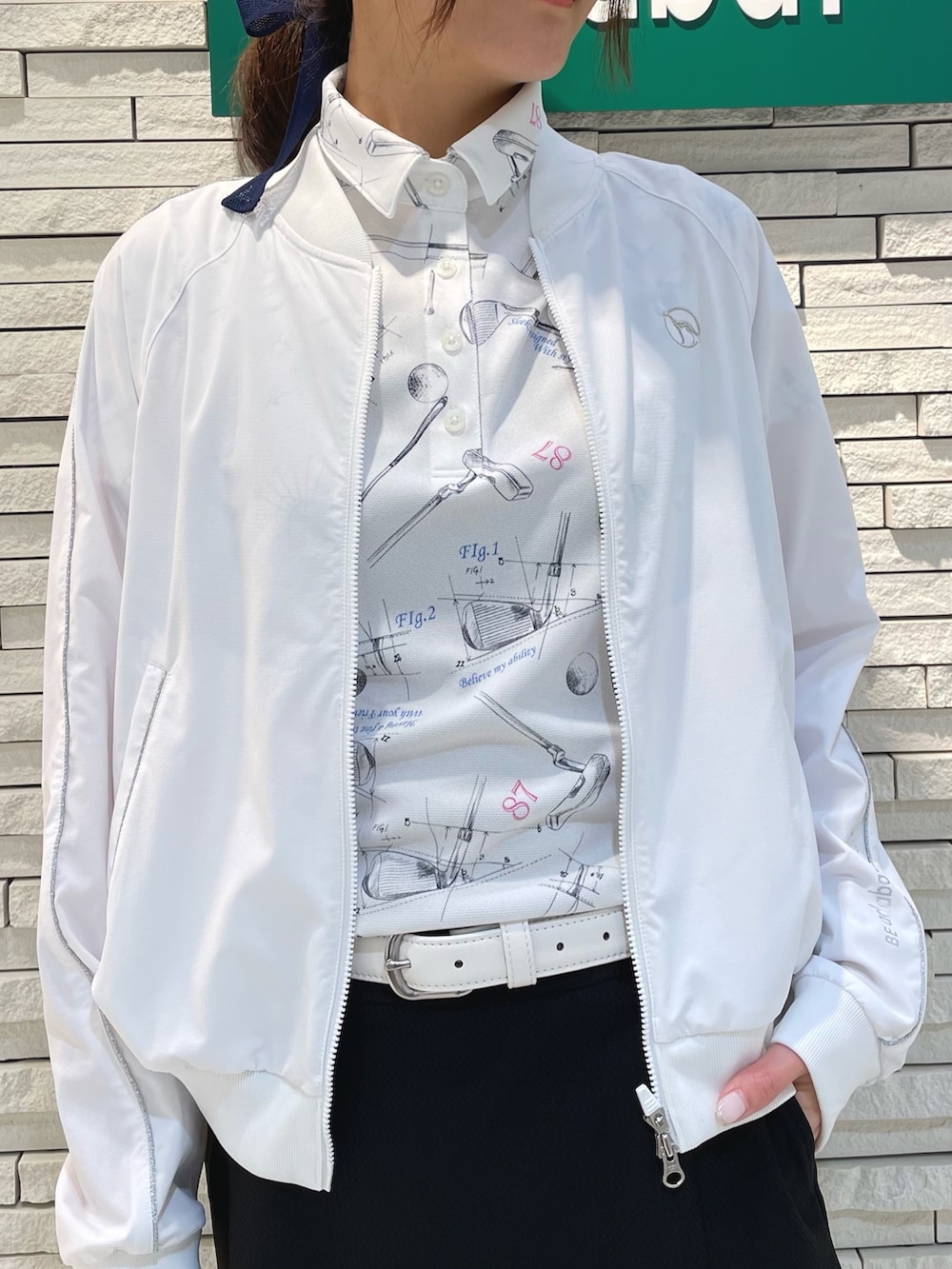 ホワイト系のブルゾン、ホワイト系のポロシャツ、ホワイト系のトートバッグを着用したレディースの春コーディネートの3枚目の写真