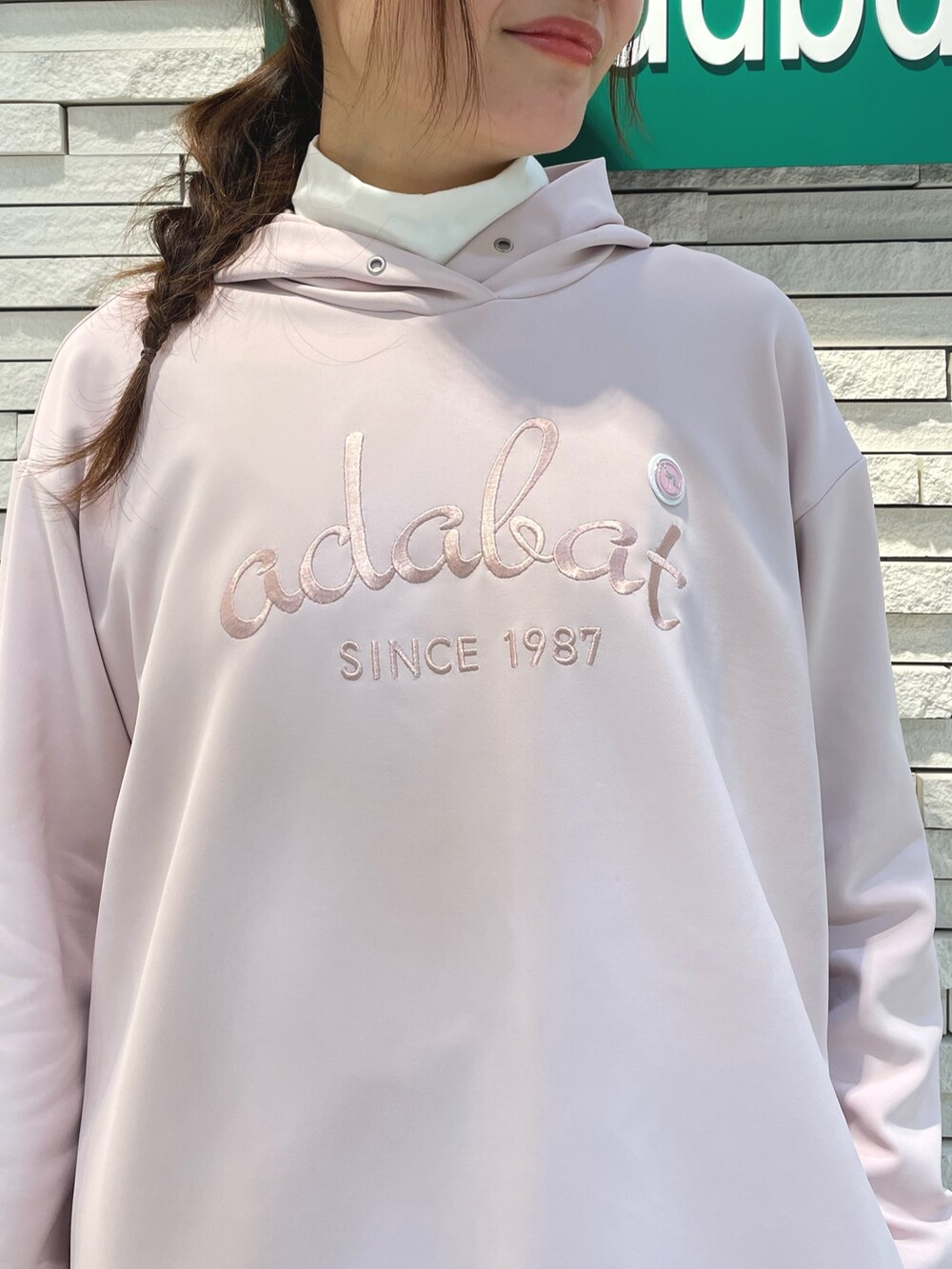 ピンク系のパーカー、ブルー系のスカート、ホワイト系のキャップを着用したレディースの春コーディネートの3枚目の写真