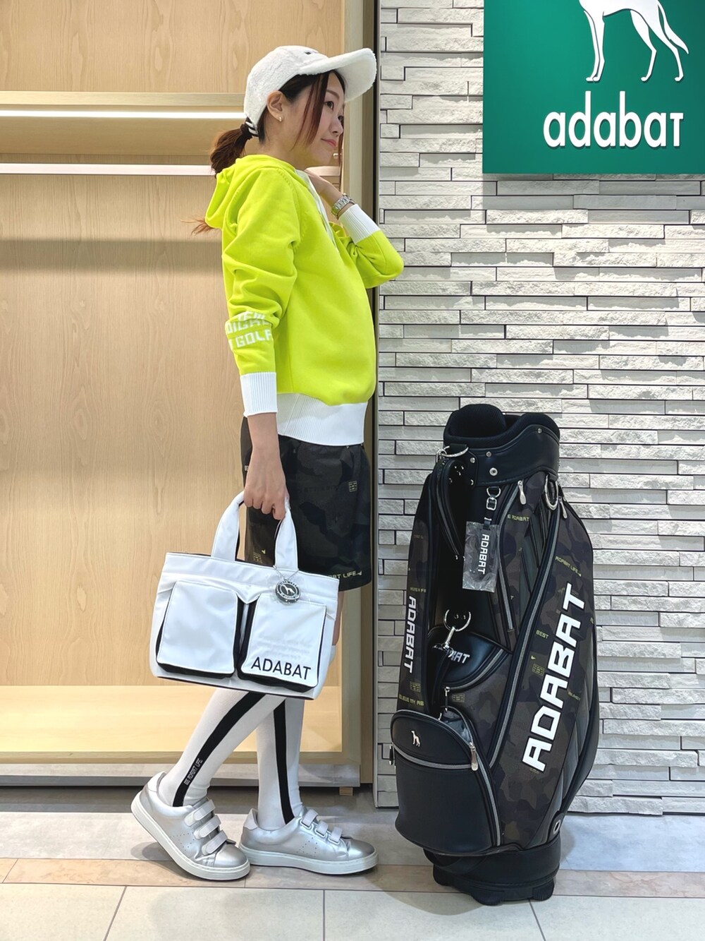 グリーン系のスカート、イエロー系のニット/セーター、ホワイト系のハンドバッグを着用したレディースの秋コーディネートの2枚目の写真