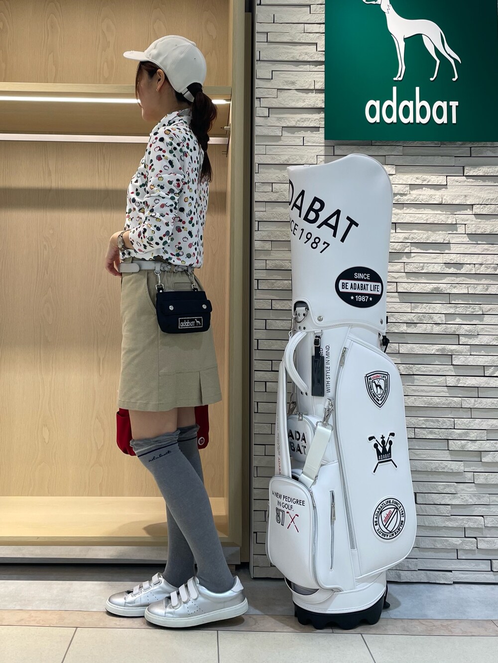 レッド系のポロシャツ、ベージュ系のスカート、レッド系のハンドバッグを着用したレディースの秋コーディネートの2枚目の写真