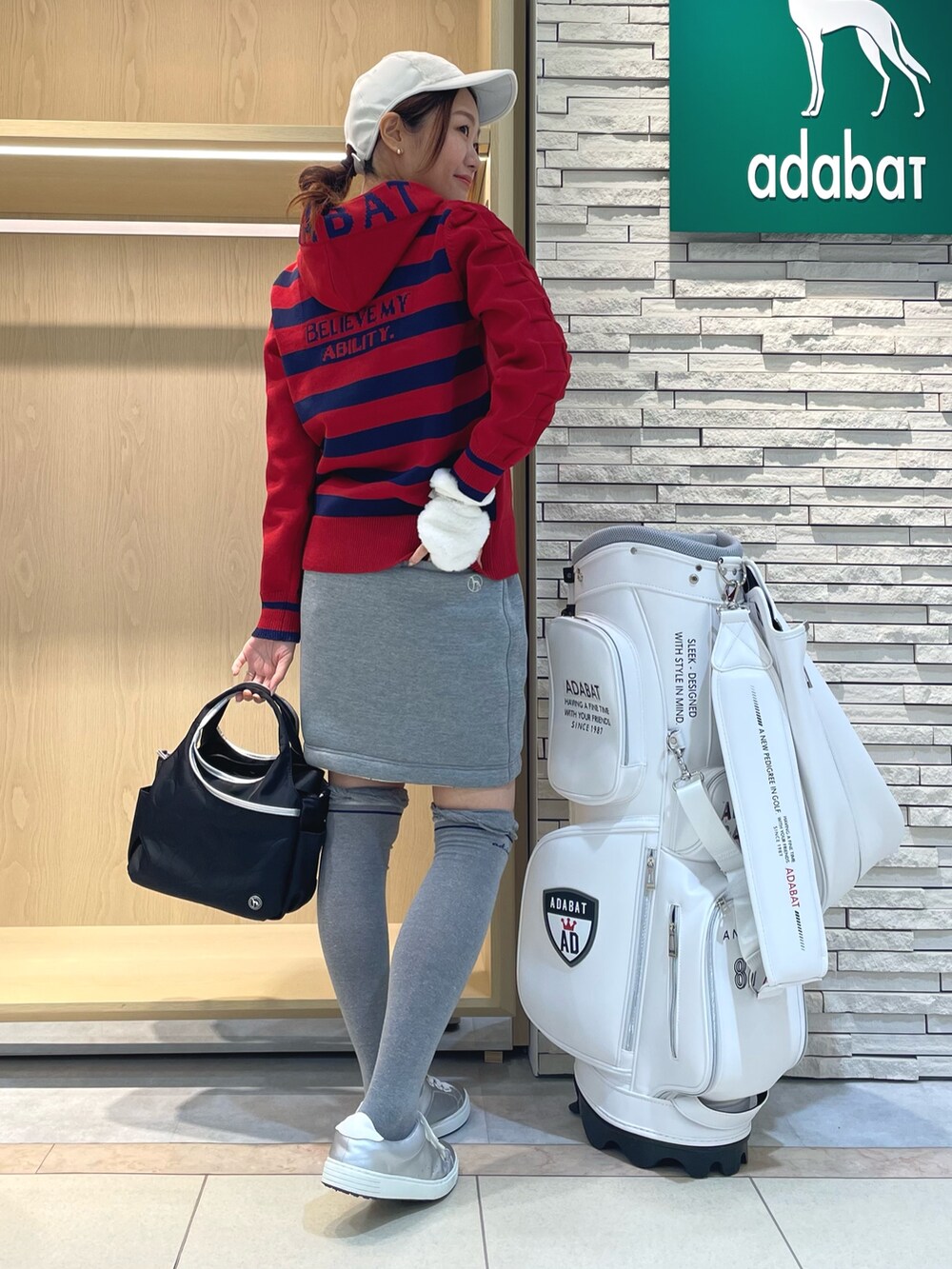 レッド系のニット/セーター、グレー系のスカート、ブラック系のハンドバッグを着用したレディースの秋コーディネートの3枚目の写真