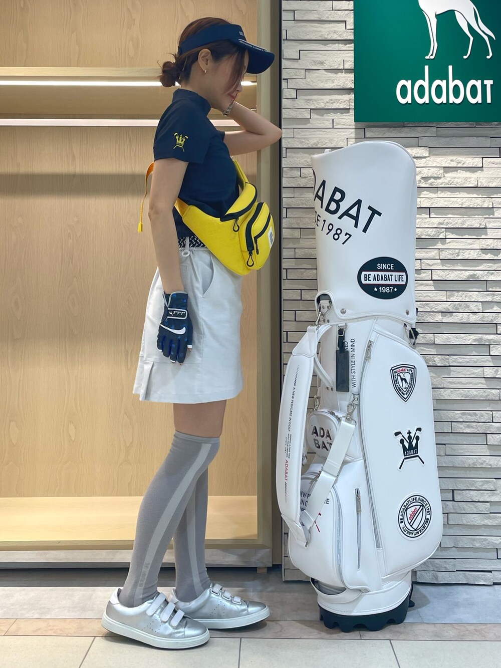 グレー系のスカート、ブルー系のTシャツ/カットソー、イエロー系のボディバッグ/ウエストポーチを着用したレディースの秋コーディネートの2枚目の写真