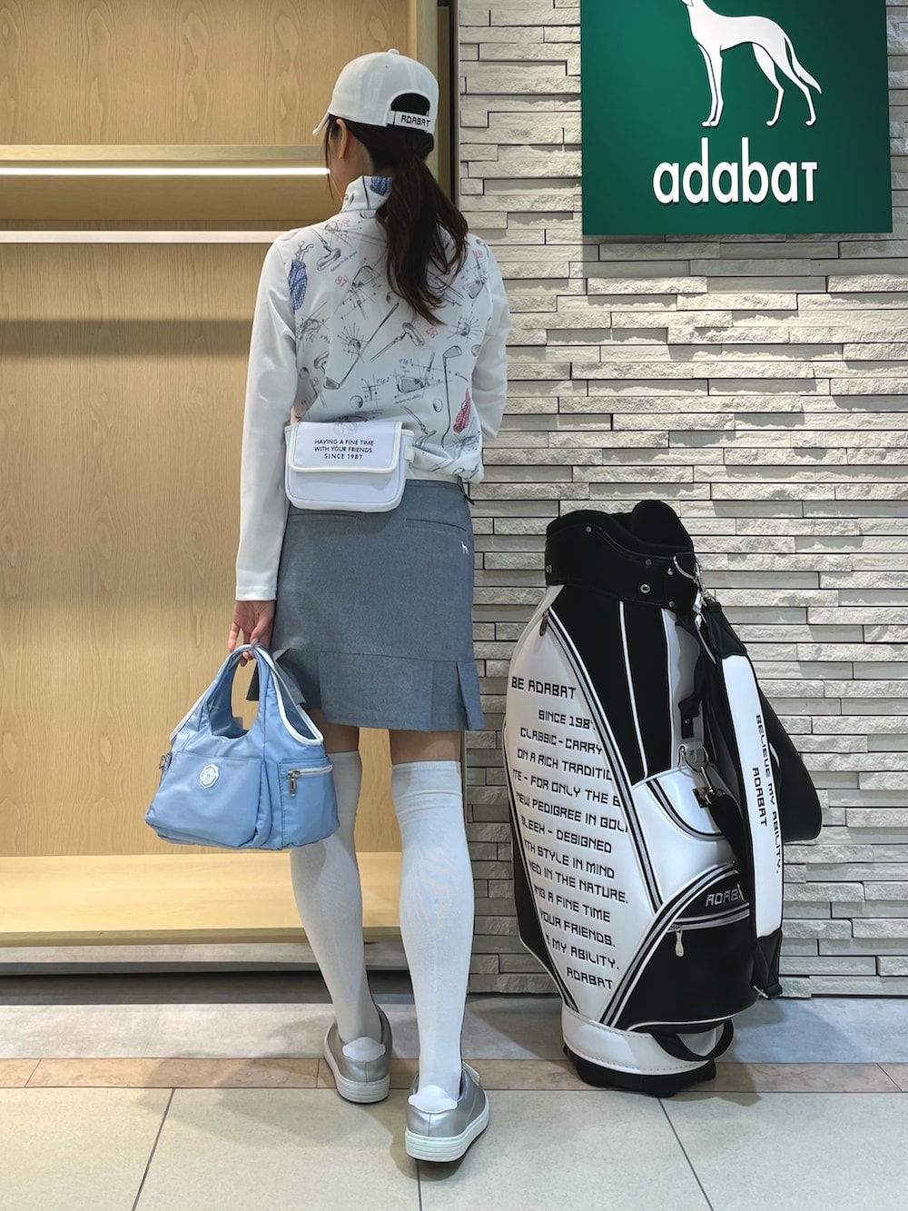 ブルー系のスカート、ホワイト系のTシャツ/カットソー、ブルー系のトートバッグを着用したレディースの春コーディネートの2枚目の写真