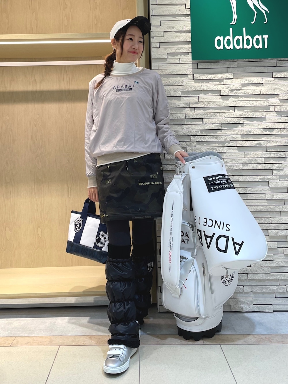 グリーン系のスカート、ホワイト系のニット/セーター、ホワイト系のTシャツ/カットソーを着用したレディースの冬コーディネートの2枚目の写真