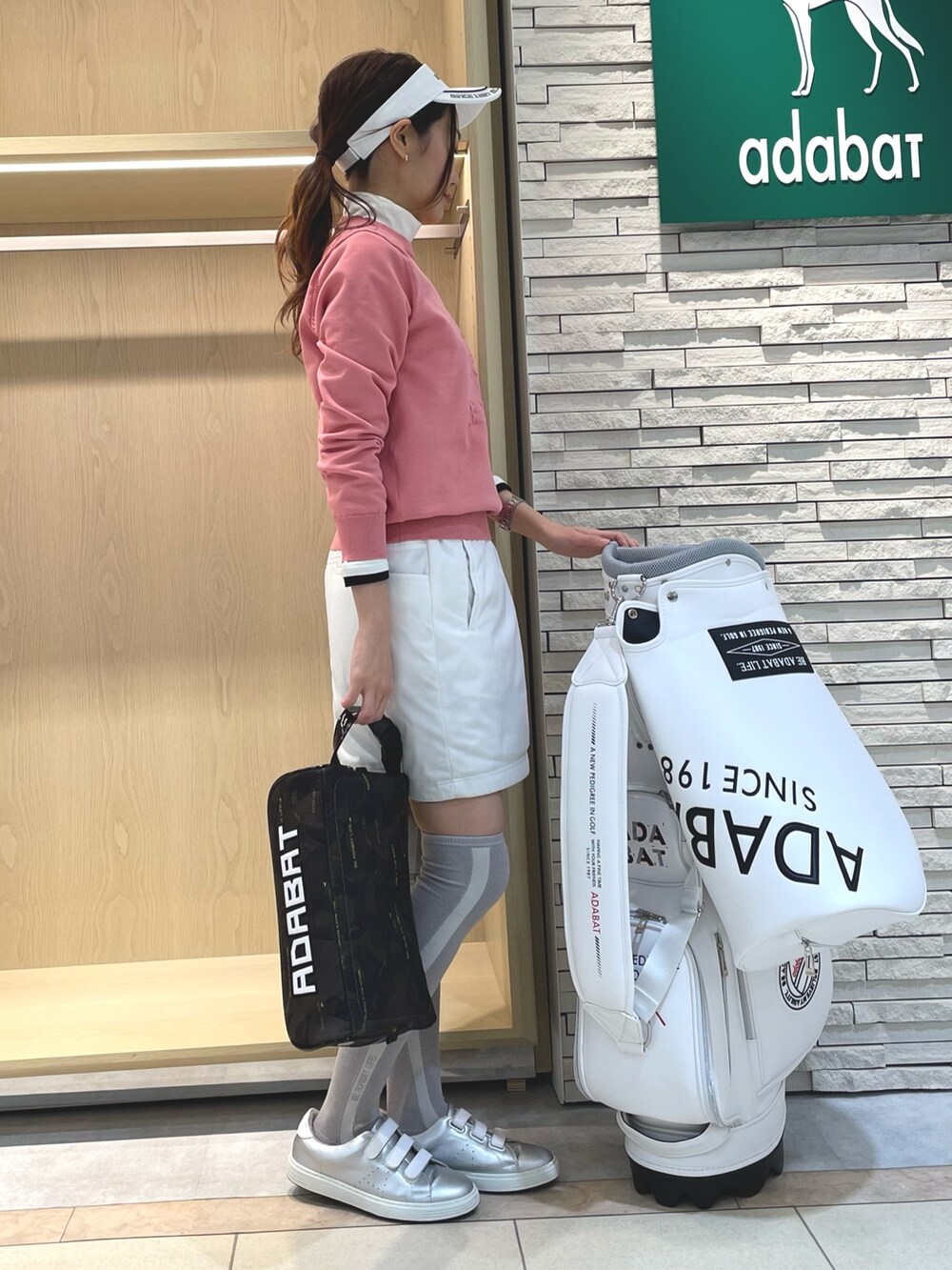 ピンク系のニット/セーター、グリーン系のスカート、ホワイト系のサンバイザーを着用したレディースの冬コーディネートの2枚目の写真