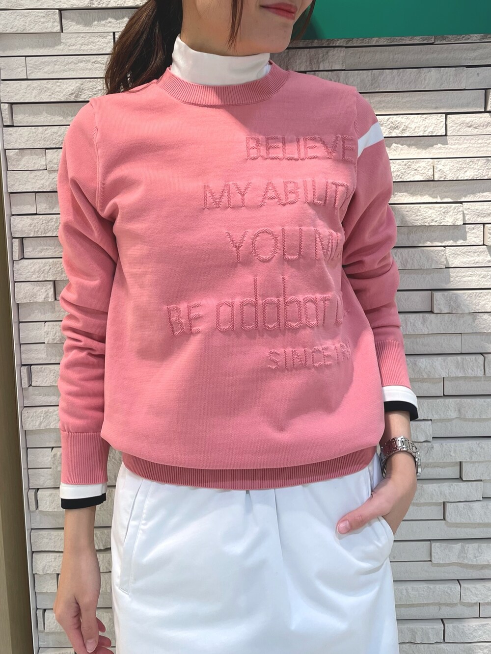 ピンク系のニット/セーター、グリーン系のスカート、ホワイト系のサンバイザーを着用したレディースの冬コーディネートの3枚目の写真