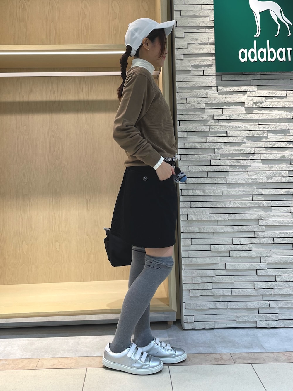 ブラック系のスカート、ベージュ系のニット/セーター、ブラック系のハンドバッグを着用したレディースの春コーディネートの2枚目の写真